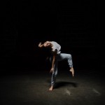 Dancer stands on right leg, left leg lifted with a bent knee, arched back towards the right side. 