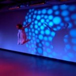 Dancer jumping with theatrical lighting on back wall