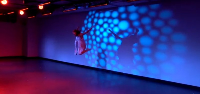Dancer jumping with theatrical lighting on back wall