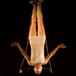 Woman hanging upsidedown from her ankles with arms outstretched