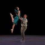 Two swing dancers - the woman is jumping as the man holds her hands