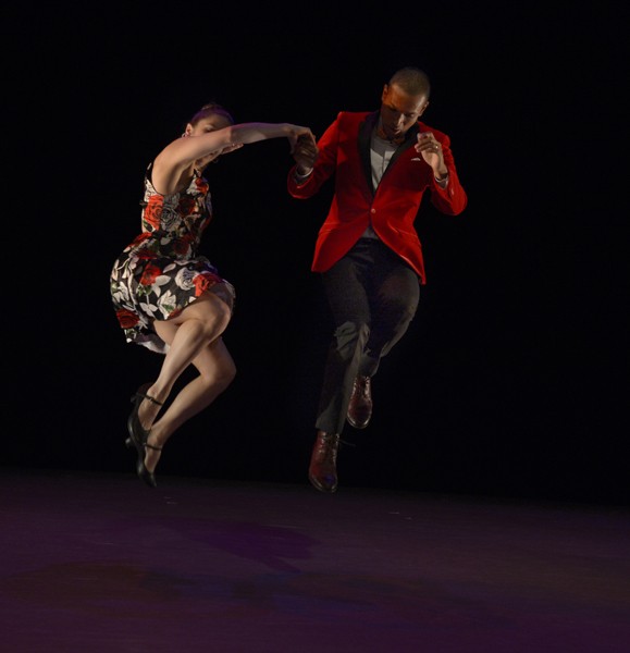 A swing dance couple jumping