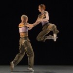 A jazz dance duet with one of the dancers in a partnered jump.