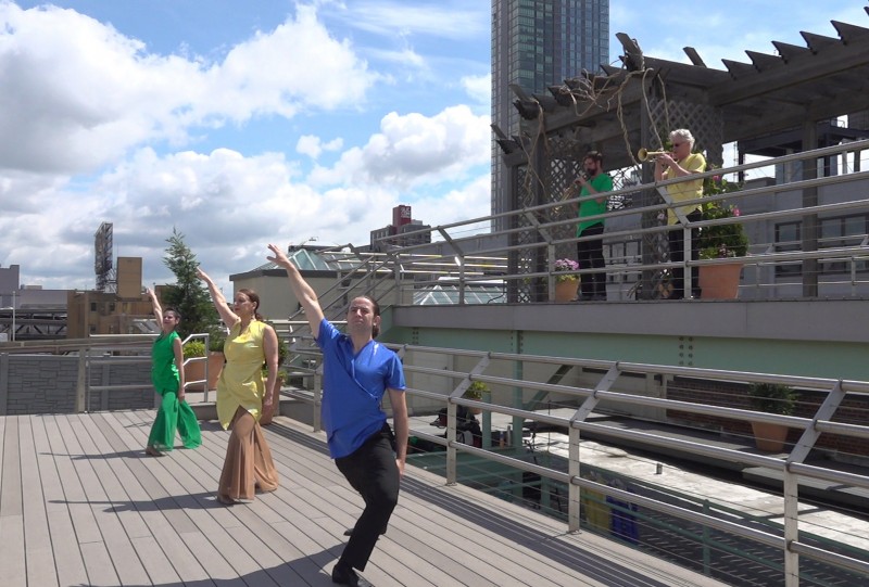 Rooftop Image: 3 dancers lunge with their right arm up, pointed skyward. 2 musicians playing saxophone and trumpet stand above.