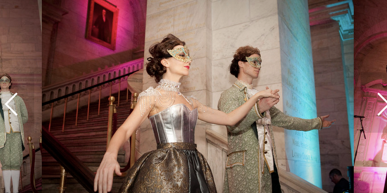 Two venetian dancers perform a partner dance in gold baroque costumes.
