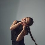 Image of Nicole von Arx dancing in front of a white wall. 