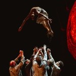 A group of dancers throwing a single dancer into the air.