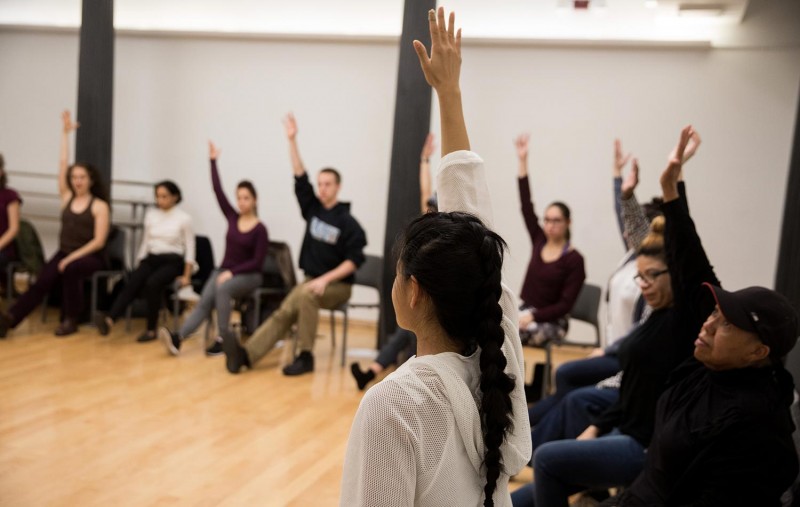 Group of people sitting in a circle with one arm raised in the air.