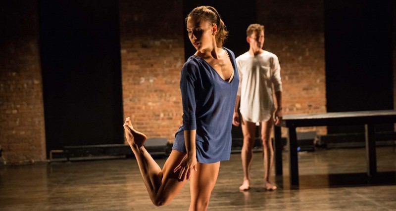 Woman on stage looking back at her leg behind her. 