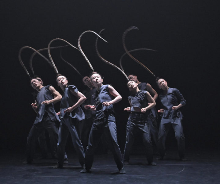 Group of dancers with feathers breezing over their heads.