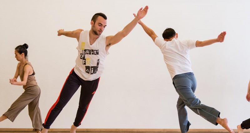 three people mid-motion dancing in a studio. 