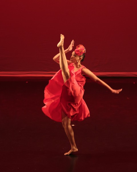 Female Dancer in Red Dress Kicking Leg to Front with opposite arm extending upward