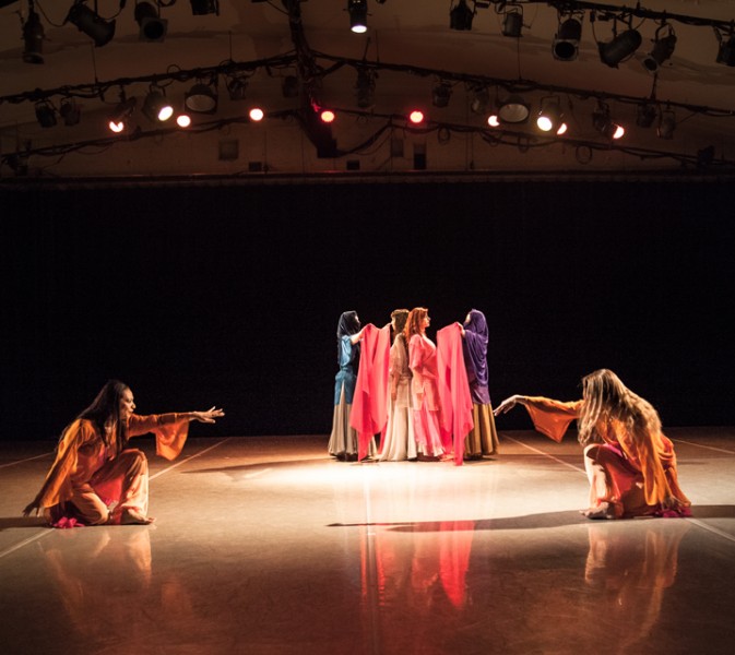 Two dancers in foreground reach toward each other; two dancers in background drape red veils over two women between them.