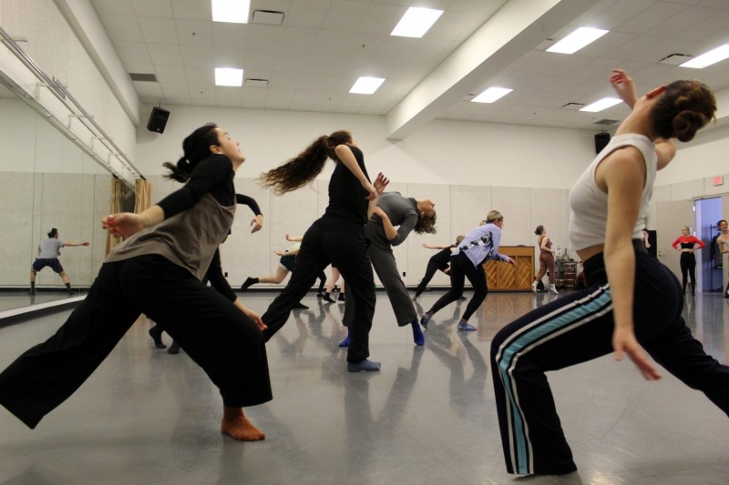 Multiple dancers in workout clothing and socks moving as a group