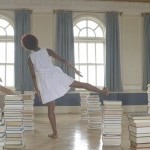 Three women standing on one leg in a room full of books.