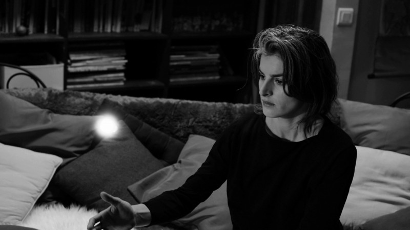 Woman sitting with hand outstretched under a floating ball of light