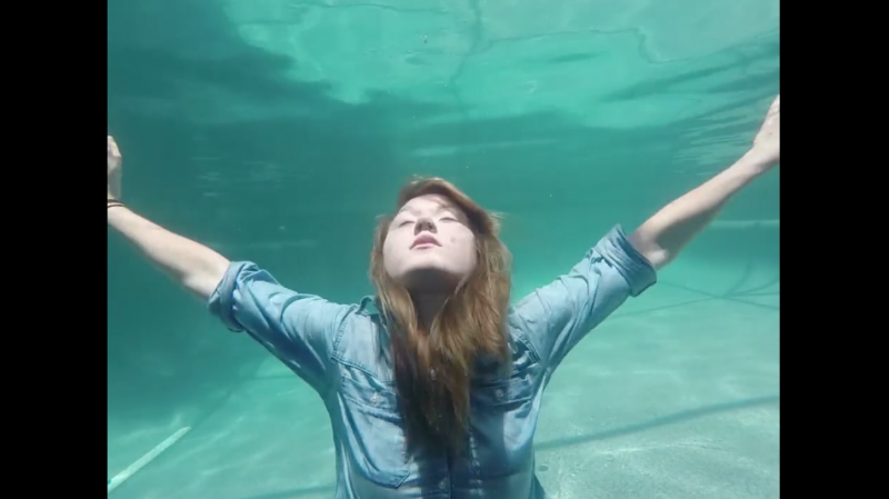 Woman under water, spreading her arms wide.