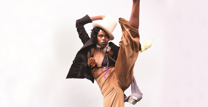 A woman dances while kicking her foot in the air.