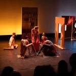 5 dancers in colorful costumes dance in an environment of stage flats, ceramics and fabric