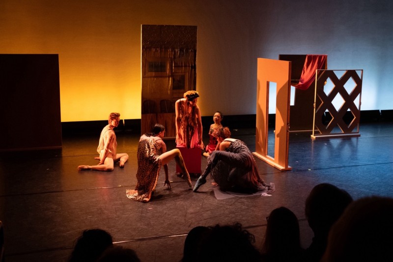 5 dancers in colorful costumes dance in an environment of stage flats, ceramics and fabric