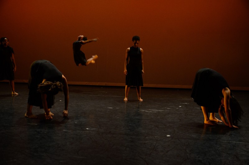 Two artists downstage swaying bent over, two artists standing in center, and one artist upstage in a c jump. 