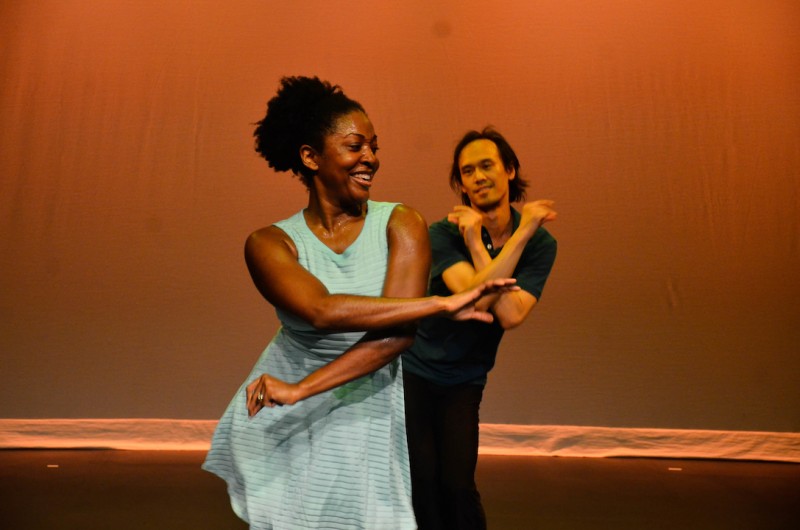 An African American woman crosses in front of an Asian American man