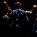 Three Performers struggling against each other in silhouette.