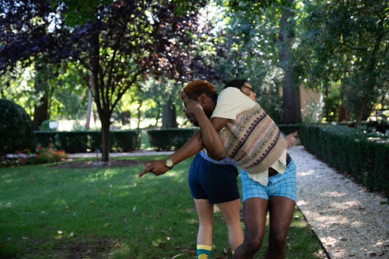 Two dancers standing back to back with arms outstretched