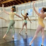 Dancers in ballet class, standing with left leg in tendu crois&eacute; devant, left arm curved up and forward, right arm extends back