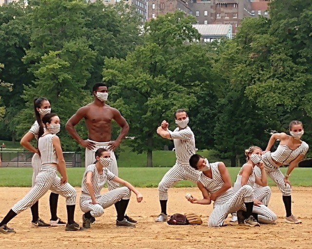 8 dancers, of multicultural backgrounds and gender, together on a baseball field in Central Park, wearing pin striped costumes.