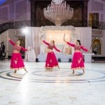 3 dancers in colorful costumes in a white, spacious event space
