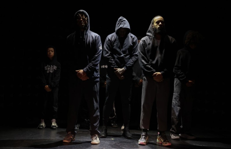 Men standing in line wearing black hoodies