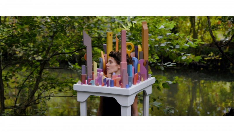 Main character singing Yeats poetry in city sculpture in natural environment.