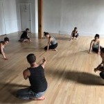 dancers sitting in a circle, learning a movement