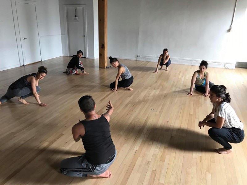 dancers sitting in a circle, learning a movement