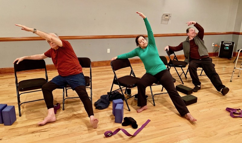 students sitting on a chair demonstrating side-angle pose 