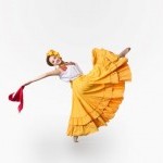 A woman in traditional Mexican dress kicks her leg in the air.