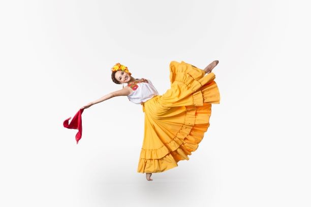 A woman in traditional Mexican dress kicks her leg in the air.