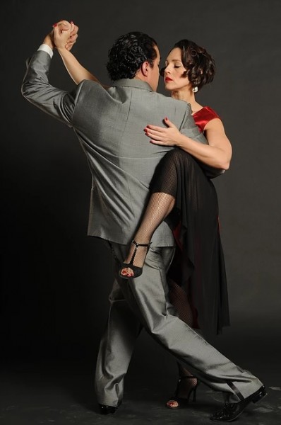 A man and woman embrace as they perform the tango. 
