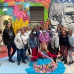Participants gather in front of colorful mural at Loisaida Center
